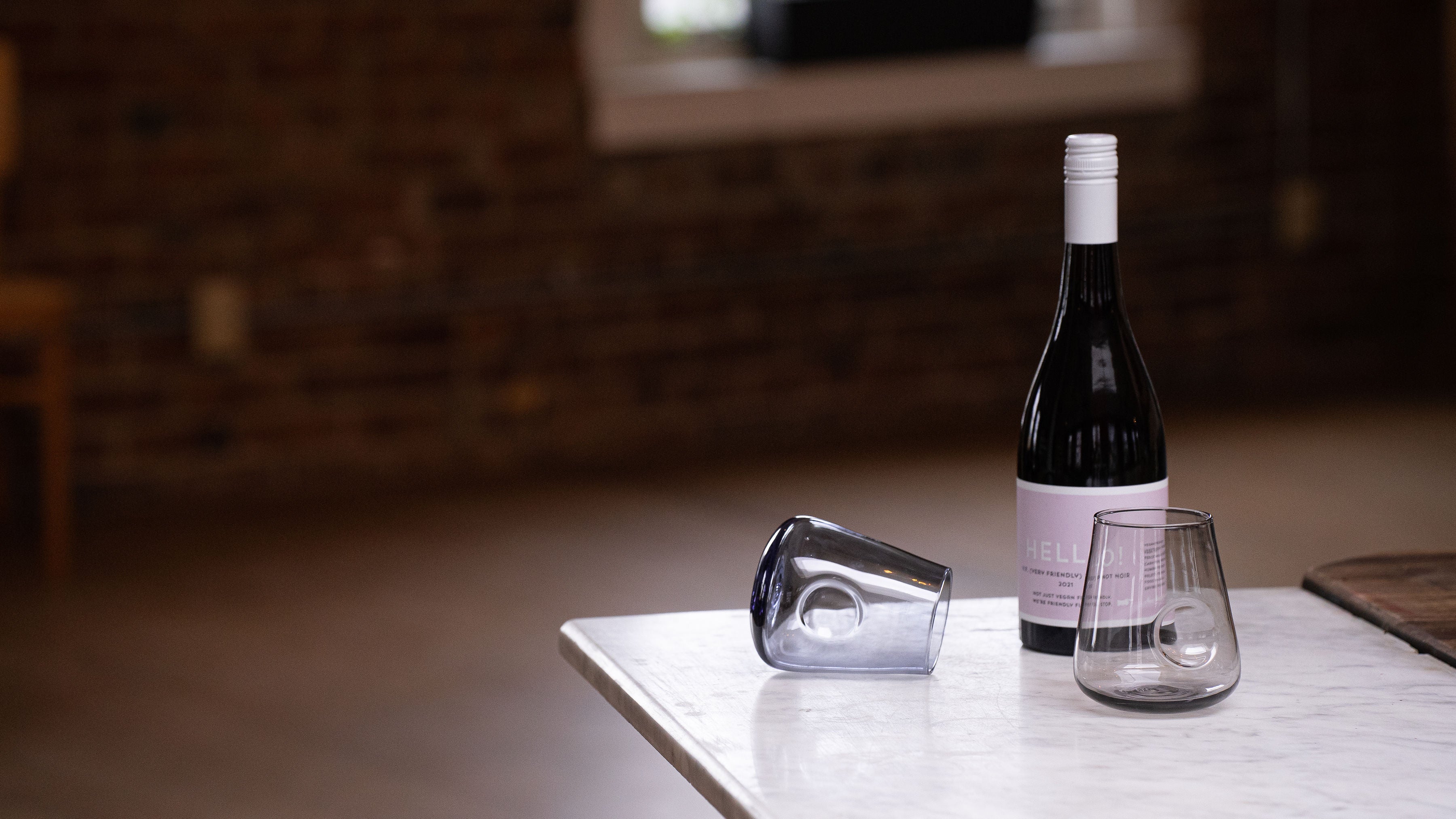 Two elegant Dougherty Glassworks stemless wine glasses alongside a wine bottle, capturing the essence of refined enjoyment and artisanal glass artistry.