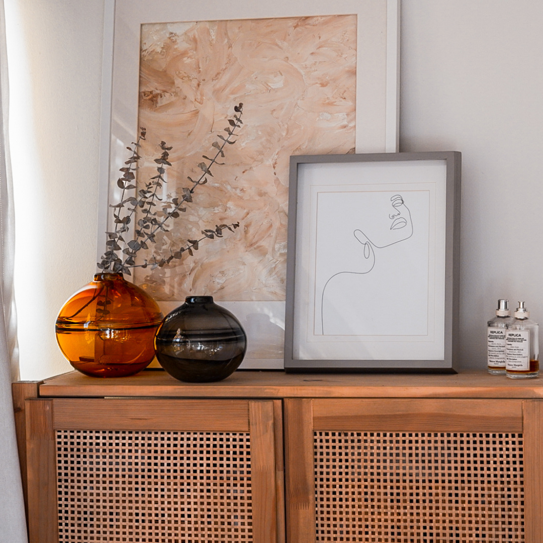 Round-bottomed halo glass vases in varying sizes, each with a small opening at the top, creating a harmonious arrangement of translucent, warm-toned spheres on a reflective surface