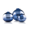 Round-bottomed halo glass vases in varying sizes, each with a small opening at the top, creating a harmonious arrangement of translucent, warm-toned spheres on a reflective surface