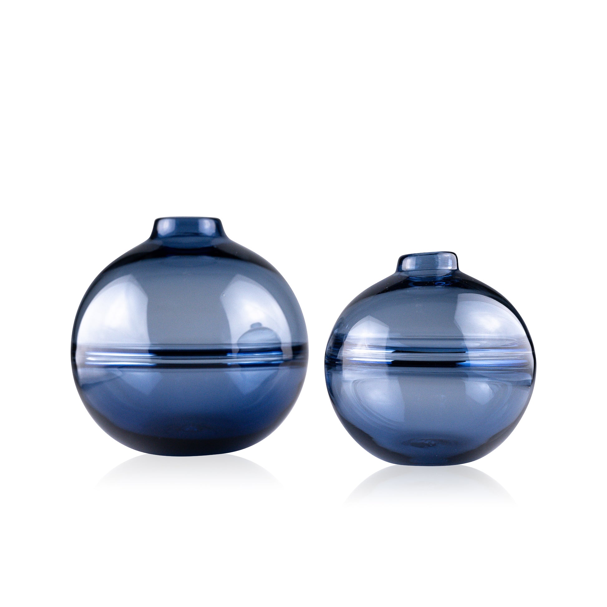 Round-bottomed halo glass vases in varying sizes, each with a small opening at the top, creating a harmonious arrangement of translucent, warm-toned spheres on a reflective surface