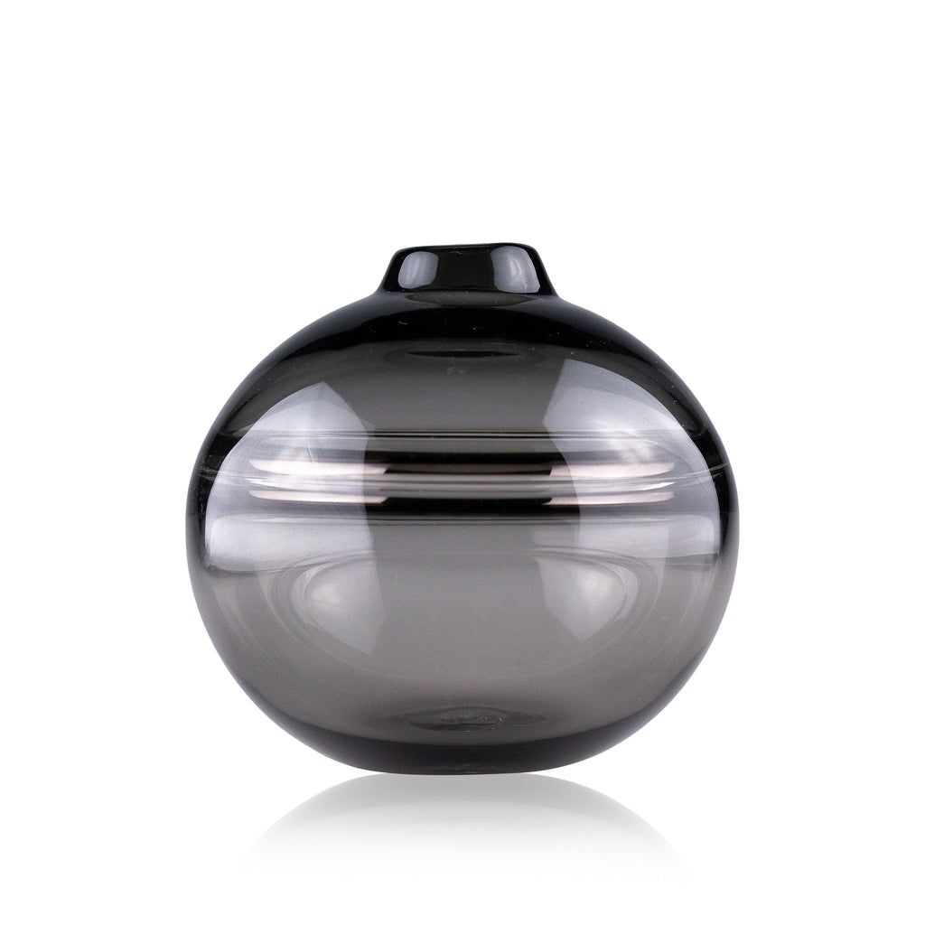 Round-bottomed halo glass vases in varying sizes, each with a small opening at the top, creating a harmonious arrangement of translucent, warm-toned spheres on a reflective surface