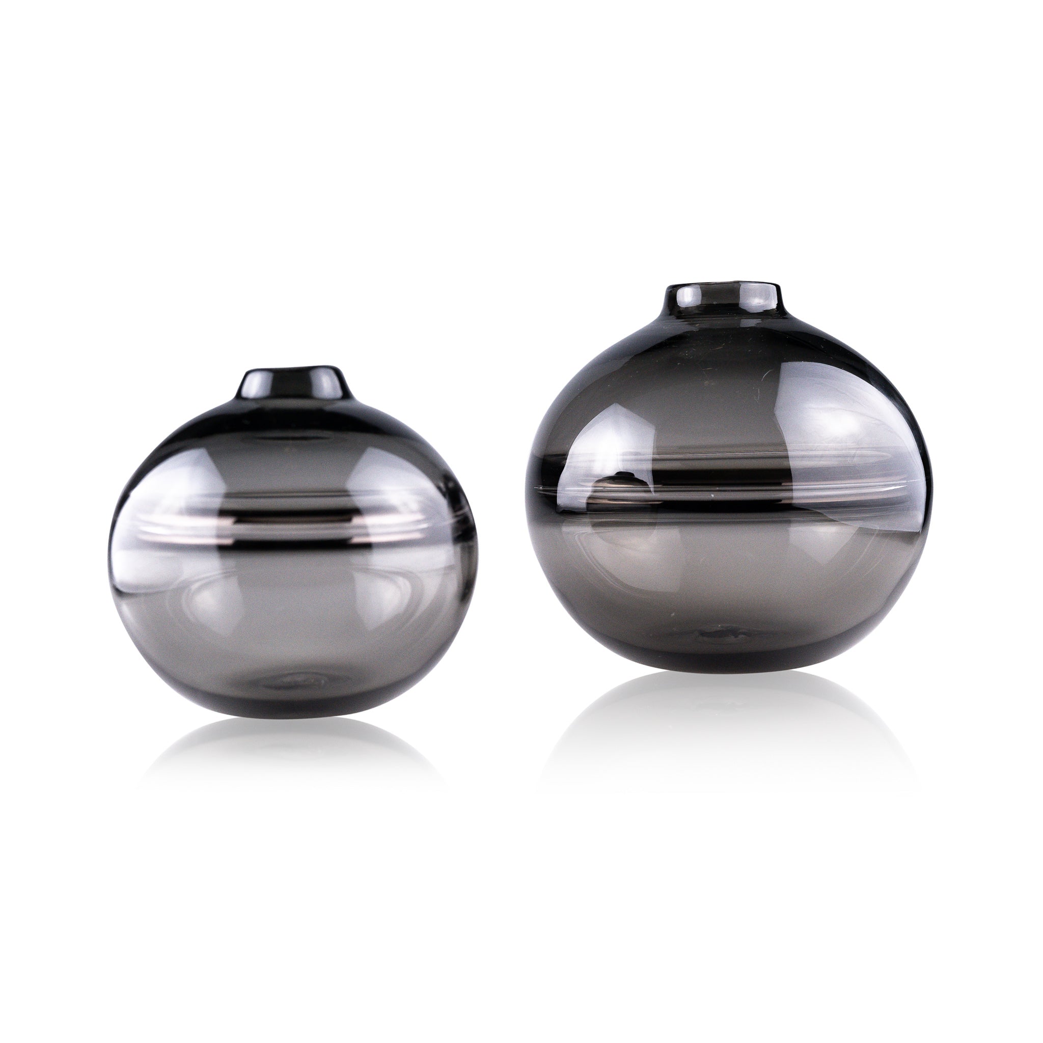 Round-bottomed halo glass vases in varying sizes, each with a small opening at the top, creating a harmonious arrangement of translucent, warm-toned spheres on a reflective surface