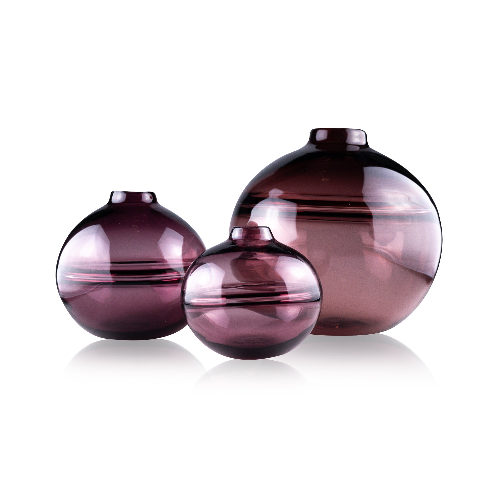 Round-bottomed halo glass vases in varying sizes, each with a small opening at the top, creating a harmonious arrangement of translucent, warm-toned spheres on a reflective surface