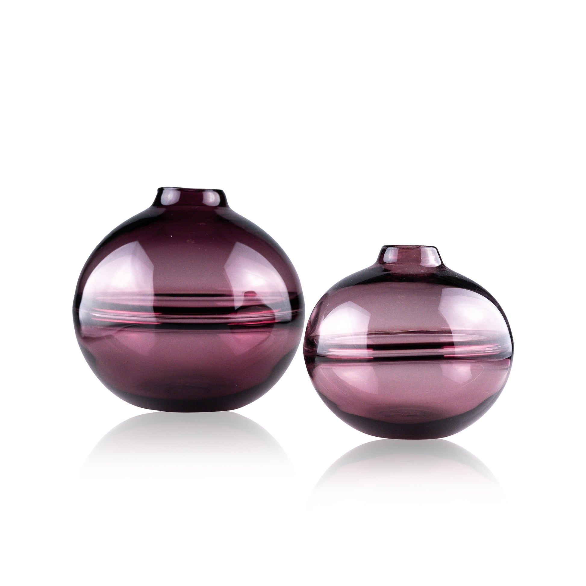 Round-bottomed halo glass vases in varying sizes, each with a small opening at the top, creating a harmonious arrangement of translucent, warm-toned spheres on a reflective surface