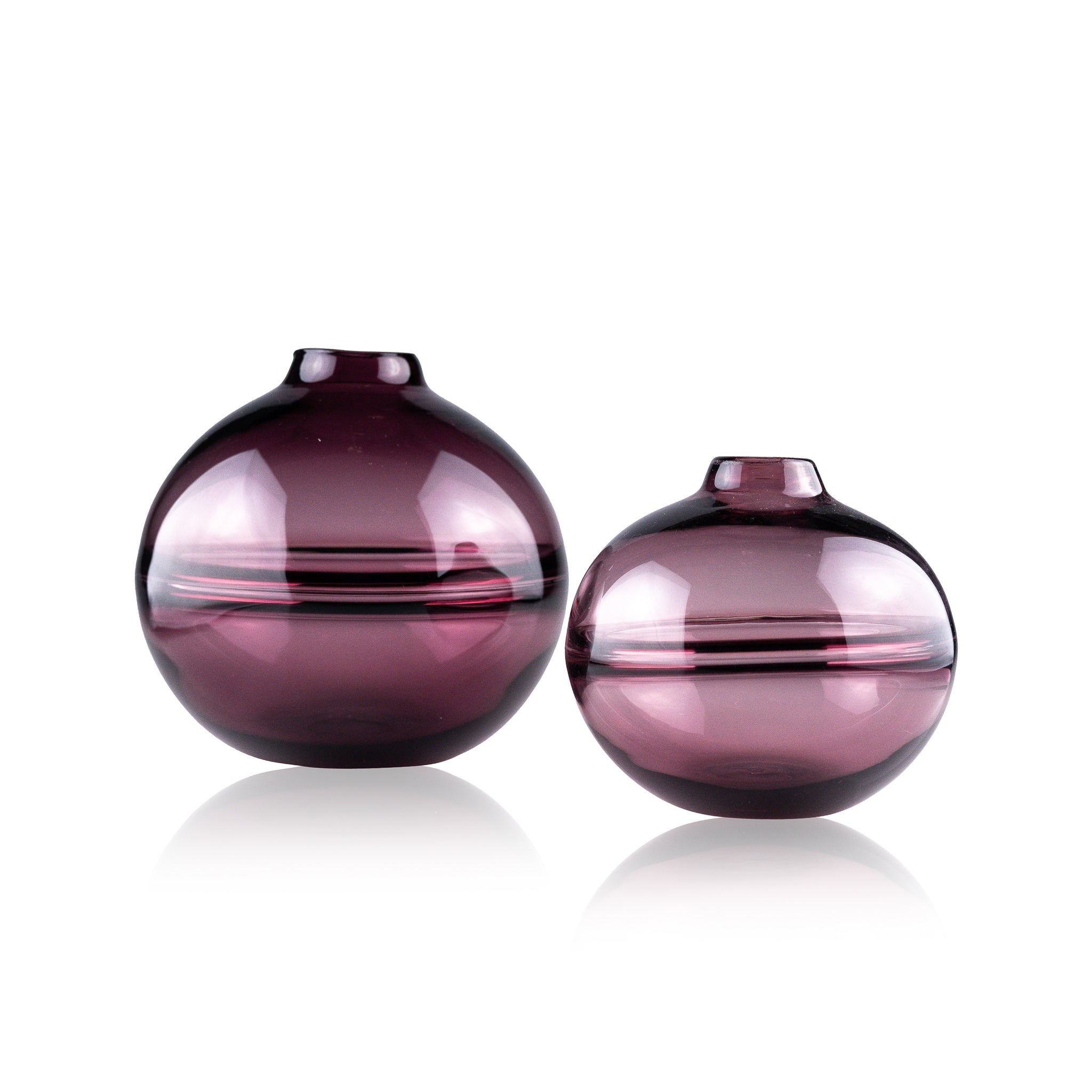 Round-bottomed halo glass vases in varying sizes, each with a small opening at the top, creating a harmonious arrangement of translucent, warm-toned spheres on a reflective surface
