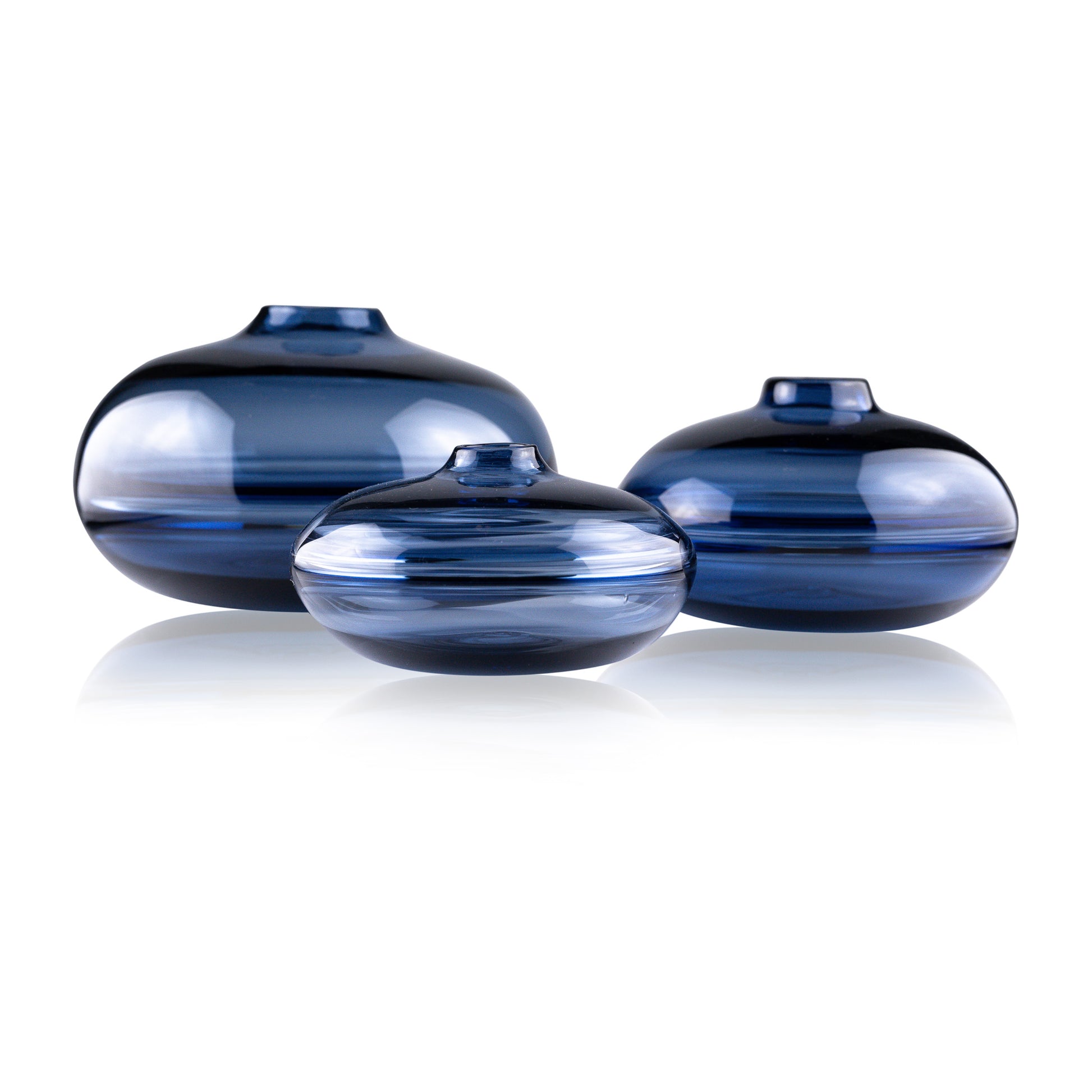 A squat glass vessel with a wide, flattened body and a narrow, raised lid, photographed against a white background, showcasing its smooth lines and tranquil, translucent color, reflective of serene, contemporary glass artistry.