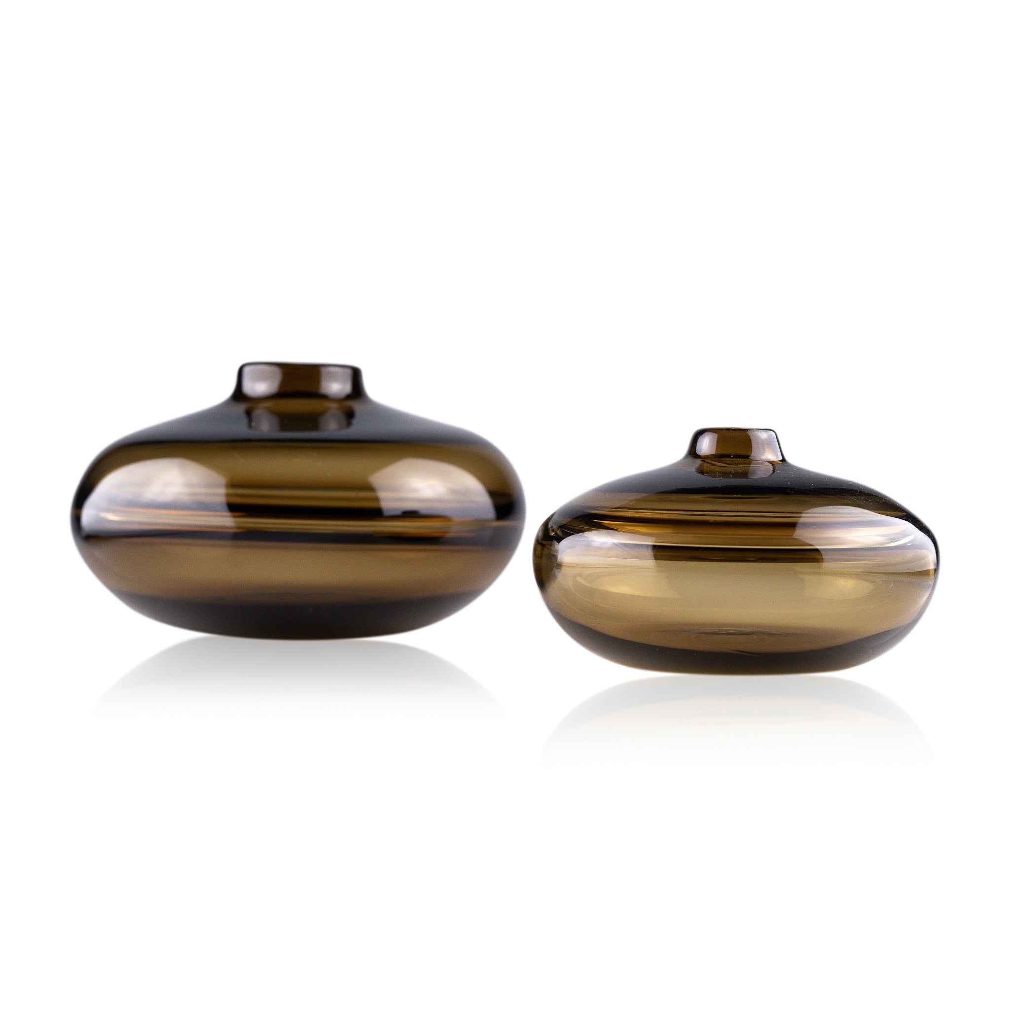 A squat glass vessel with a wide, flattened body and a narrow, raised lid, photographed against a white background, showcasing its smooth lines and tranquil, translucent color, reflective of serene, contemporary glass artistry.