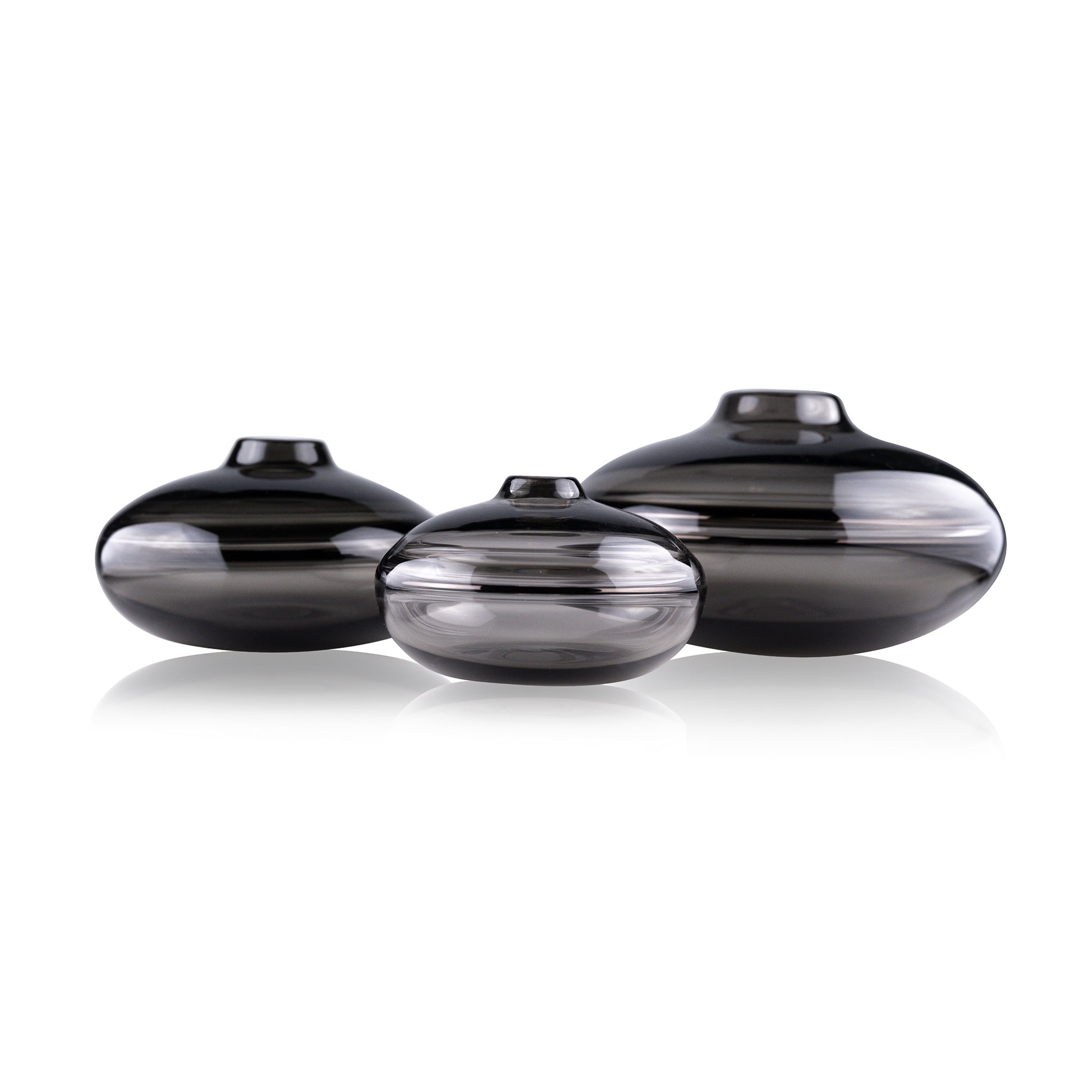 A squat glass vessel with a wide, flattened body and a narrow, raised lid, photographed against a white background, showcasing its smooth lines and tranquil, translucent color, reflective of serene, contemporary glass artistry.