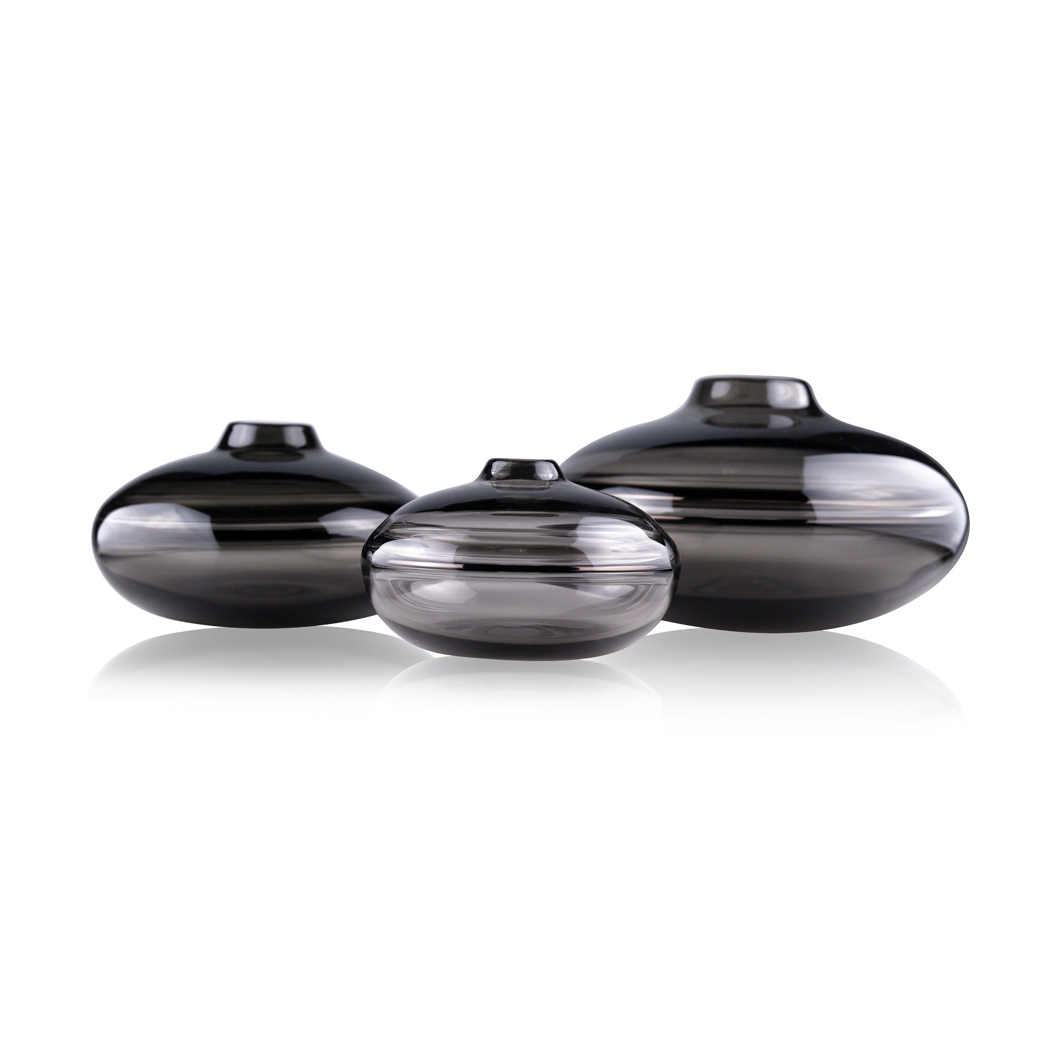 A squat glass vessel with a wide, flattened body and a narrow, raised lid, photographed against a white background, showcasing its smooth lines and tranquil, translucent color, reflective of serene, contemporary glass artistry.