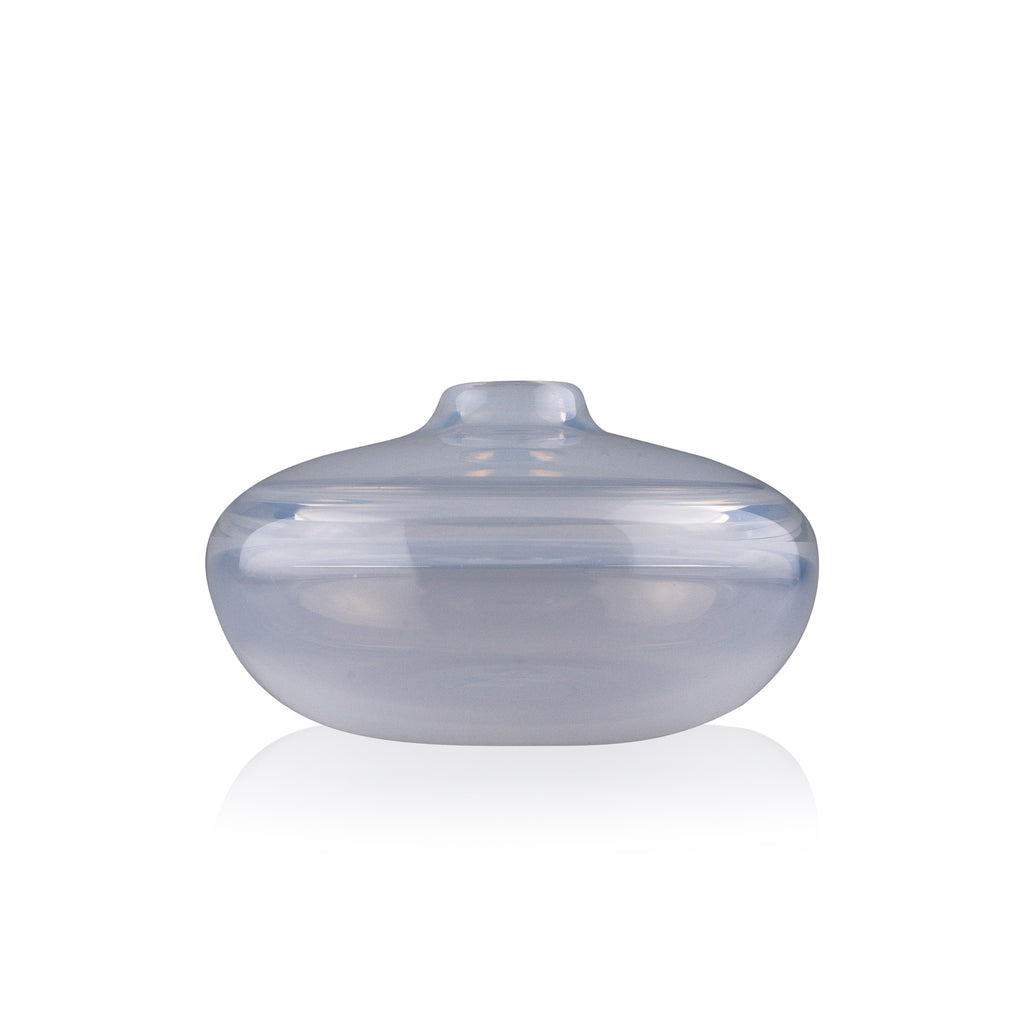 A squat glass vessel with a wide, flattened body and a narrow, raised lid, photographed against a white background, showcasing its smooth lines and tranquil, translucent color, reflective of serene, contemporary glass artistry.
