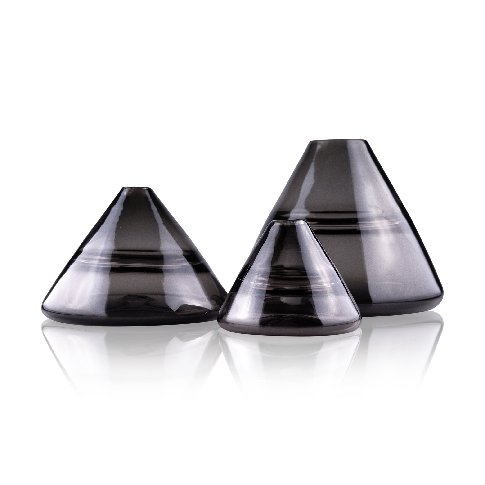 Unconventional halo vase with a conical shape, arranged in a staggered formation and reflected on a glossy surface, highlighting their sleek and contemporary design.