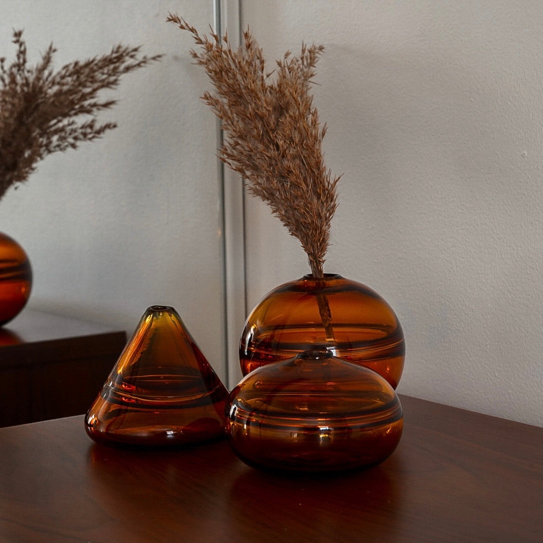 Unconventional halo vase with a conical shape, arranged in a staggered formation and reflected on a glossy surface, highlighting their sleek and contemporary design.